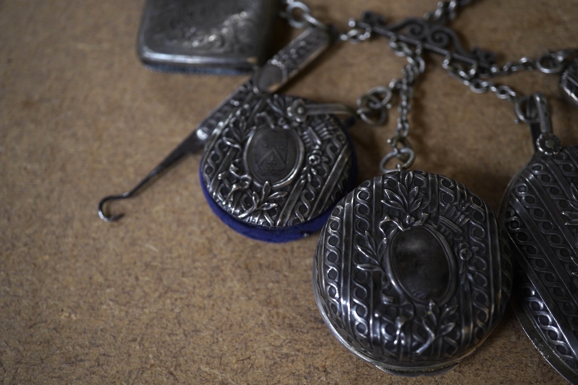 An early 20th century French white metal chatelaine, hung with six accoutrements including an associated silver vesta case, overall 35cm. Condition - fair